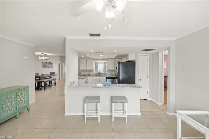 Kitchen featuring freestanding refrigerator, stainless steel dishwasher, visible vents, and light tile patterned floors