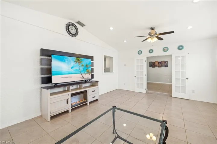 Unfurnished living room featuring a ceiling fan, french doors, visible vents, light tile patterned floors, and lofted ceiling