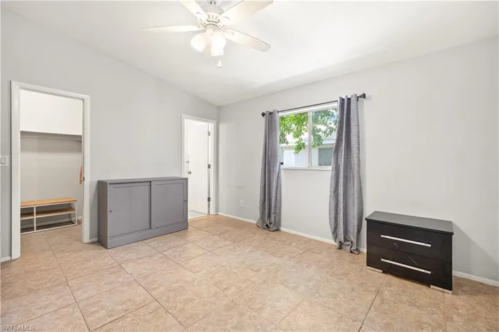 Unfurnished bedroom with a closet, lofted ceiling, baseboards, a spacious closet, and a ceiling fan