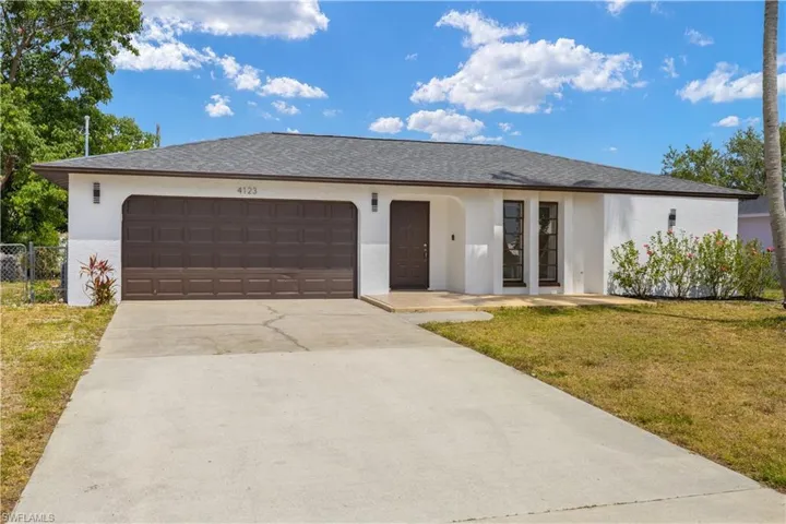 Single story home with stucco siding, an attached garage, driveway, and a front yard