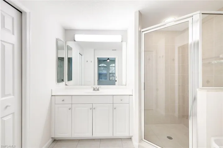 Bathroom featuring tile patterned floors, vanity, ceiling fan, and walk in shower