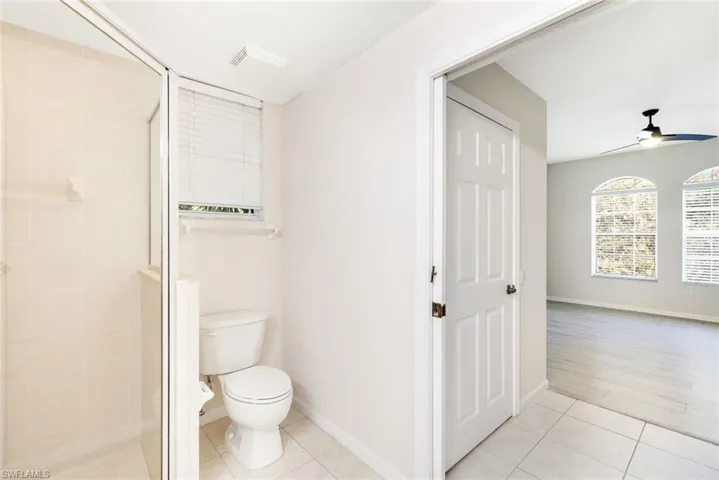 Bathroom with an enclosed shower, wood-type flooring, toilet, and ceiling fan