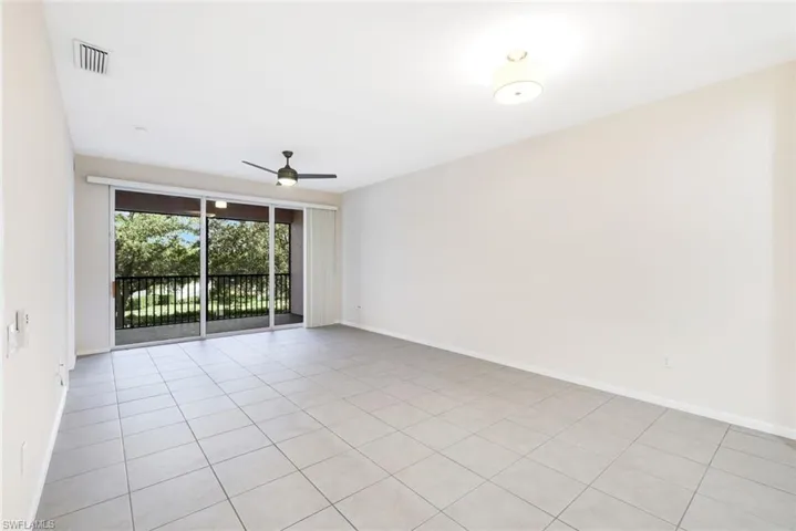 Empty room with ceiling fan and light tile patterned floors