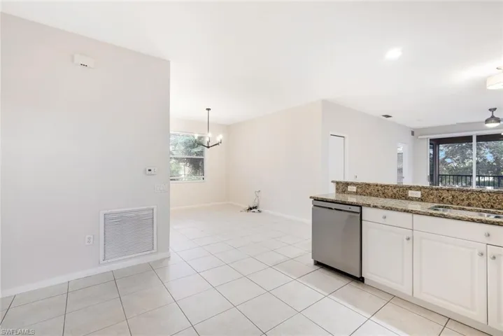 Kitchen with white cabinets, sink, stone countertops, dishwasher, and hanging light fixtures