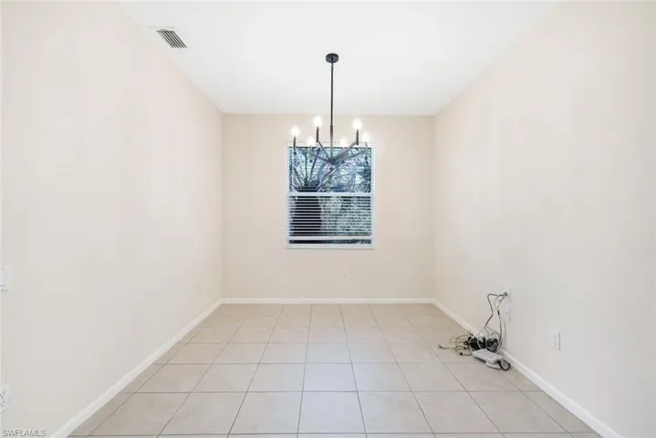 Unfurnished dining area with light tile patterned flooring and an inviting chandelier