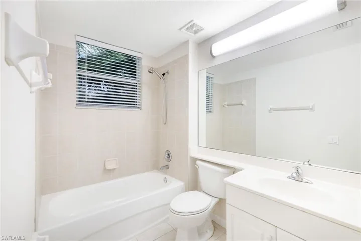 Full bathroom with tile patterned floors, vanity, tiled shower / bath combo, and toilet