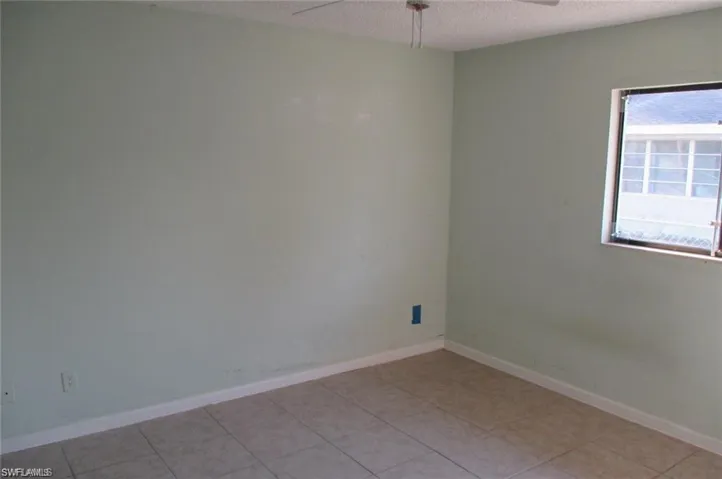 Empty room featuring a textured ceiling, ceiling fan, and light tile patterned floors