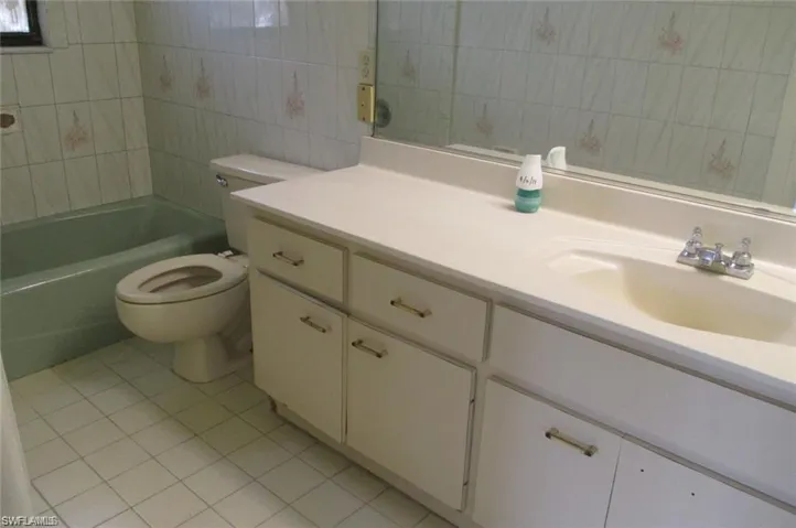 Full bath featuring light tile patterned flooring, vanity, tile walls, and shower / tub combination