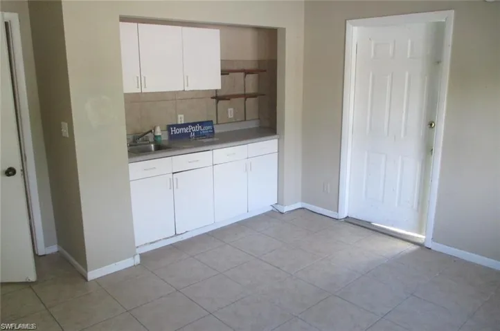 Kitchen featuring white cabinetry, light countertops, light tile patterned floors, and backsplash