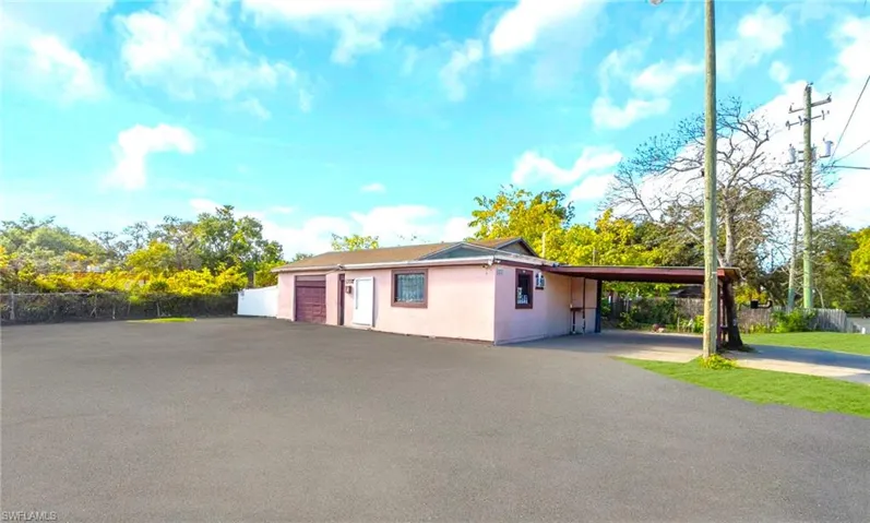 View of side of home with stucco siding, driveway, a carport, and a garage