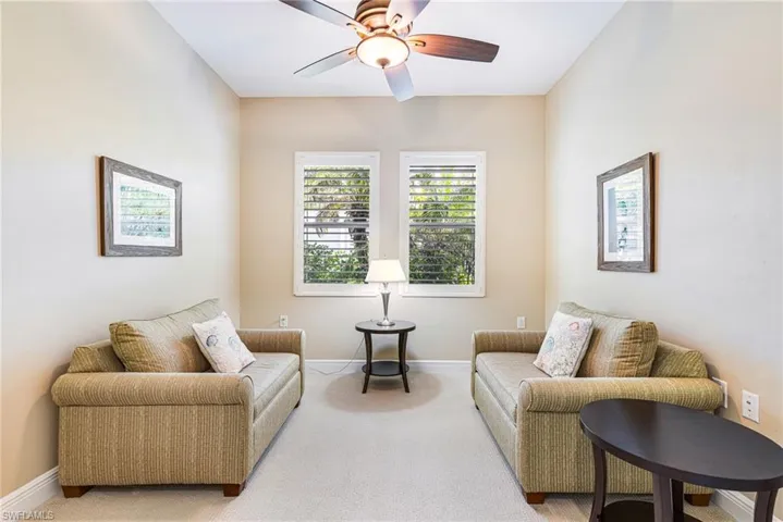 Den/Flex room used as a sitting room and for overflow guests. Features windows with plantation shutters, neutral colors and floors and a ceiling fan