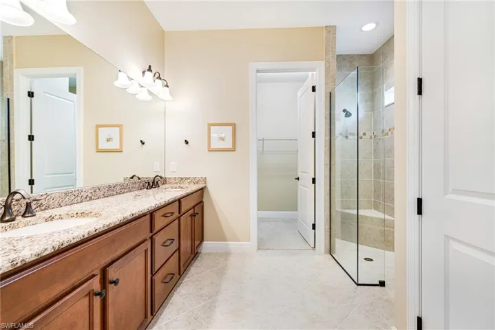 Primary Bathroom with a walk-in shower, double vanity, a spacious closet, and light tile patterned flooring