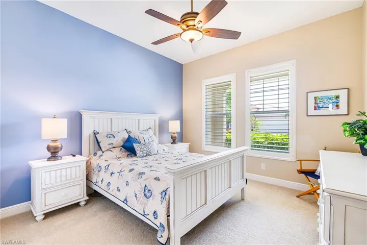 Guest Bedroom with light neutral colors, a ceiling fan, and shutters.