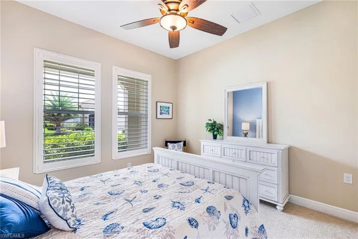 Guest bedroom featuring neutral colors, plantation shutters for natural light.
