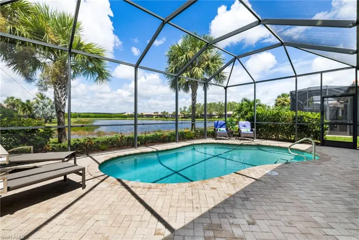 Lakeside view of pool within screened cage, a water view, seating area.