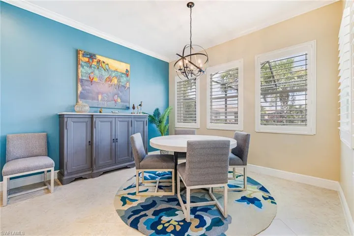 Dining area featuring plantation shutters, chandelier, accent wall with ample space for sizable seating and buffet.