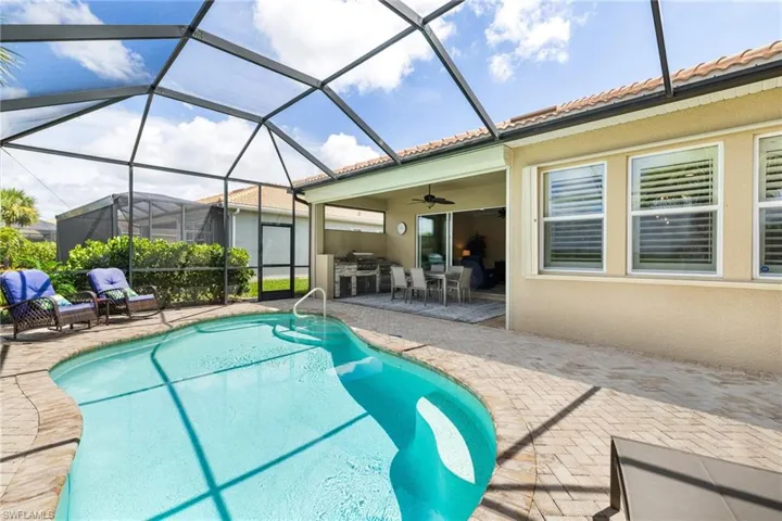 Pool with screened cage featuring a sitting area, an outdoor kitchen, and a lanai