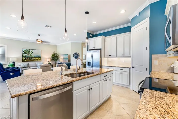 Kitchen featuring white cabinets, stainless steel appliances, a ceiling fan, crown molding, and tasteful backsplash