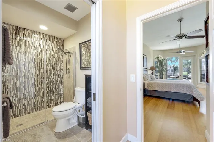 Ensuite bathroom with visible vents, toilet, a stall shower, ensuite bath, and ceiling fan
