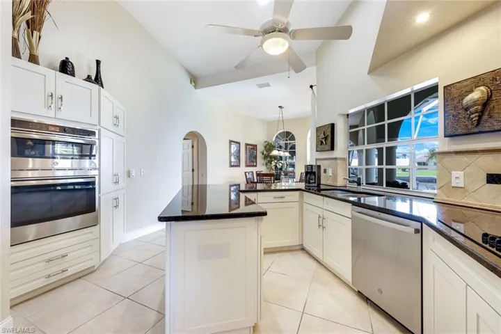 Kitchen featuring a peninsula, arched walkways, a sink, ceiling fan, and stainless steel appliances