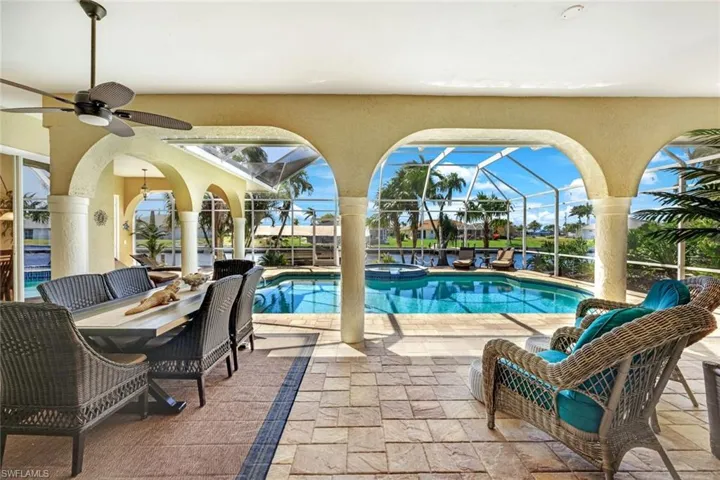 View of pool featuring glass enclosure, a pool with connected hot tub, a ceiling fan, and a patio