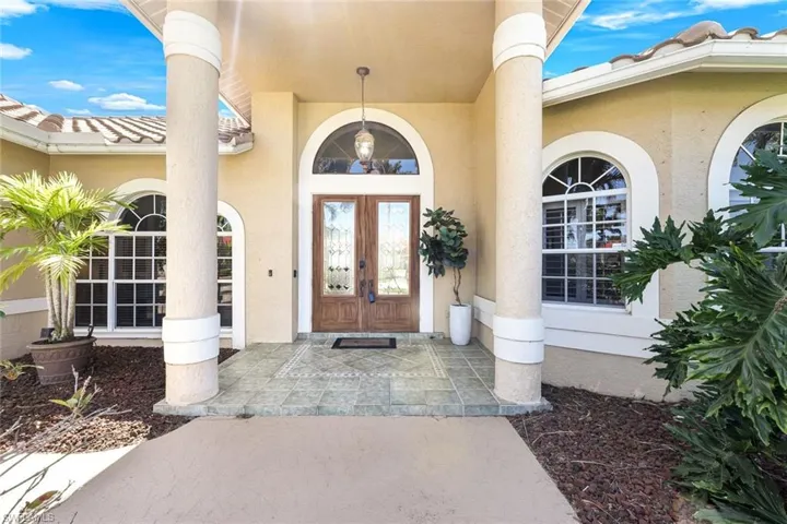 Doorway to property with a tiled roof, french doors, and stucco siding