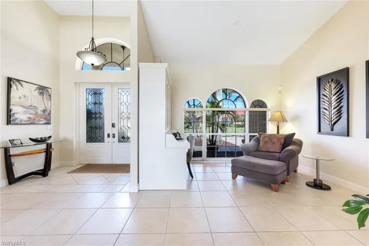 Entrance foyer with light tile patterned floors, baseboards, and high vaulted ceiling