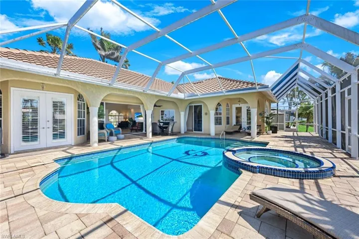 View of swimming pool featuring french doors, a patio, glass enclosure, and a pool with connected hot tub
