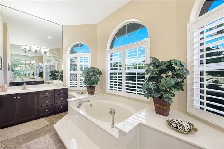 Bathroom with a notable chandelier, vanity, and a garden tub