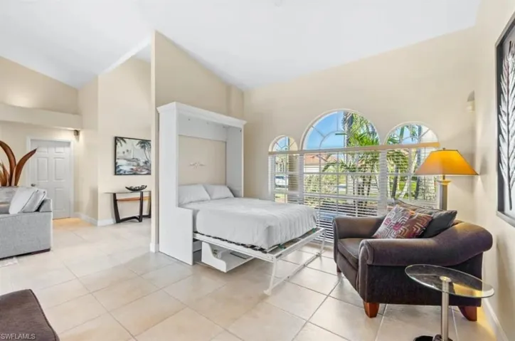 Bedroom with light tile patterned floors, high vaulted ceiling, and baseboards