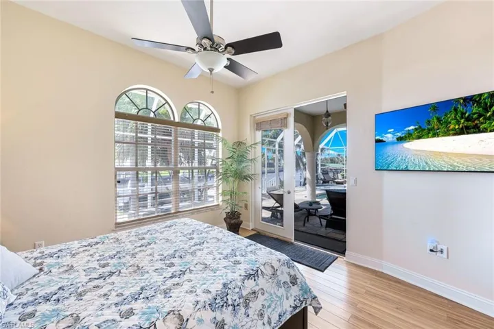 Bedroom with light wood-style flooring, baseboards, access to exterior, and a ceiling fan