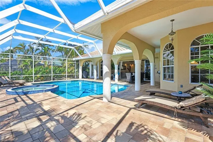 View of swimming pool featuring a patio area, a pool with connected hot tub, and a lanai