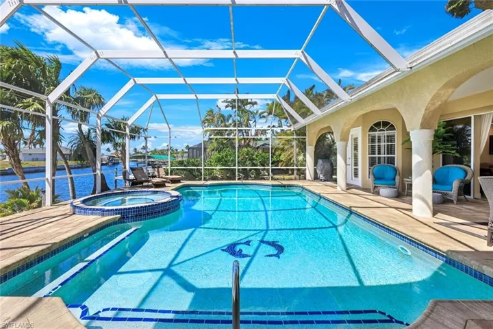 View of pool featuring a lanai, a pool with connected hot tub, a patio, and a water view