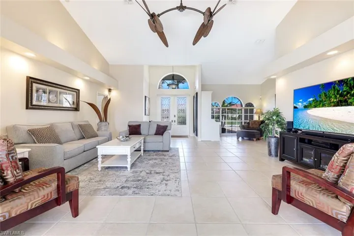 Living area featuring light tile patterned flooring, french doors, high vaulted ceiling, and a ceiling fan