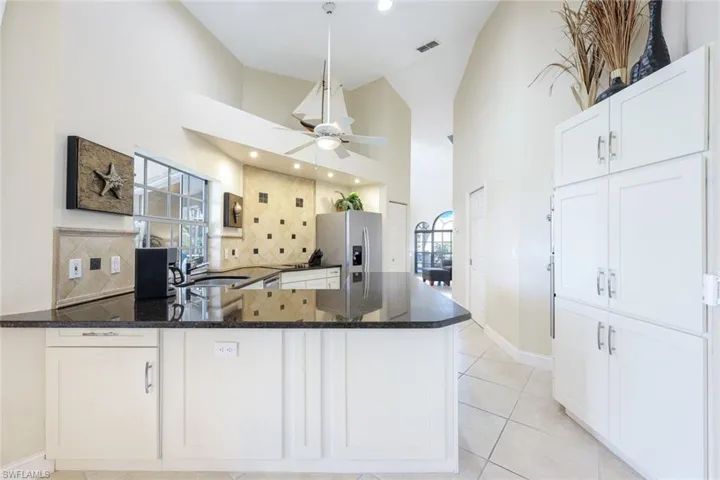 Kitchen with visible vents, a ceiling fan, a sink, dark stone countertops, and stainless steel appliances