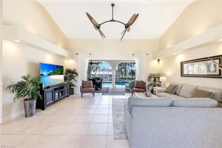Living room featuring light tile patterned floors, baseboards, and high vaulted ceiling