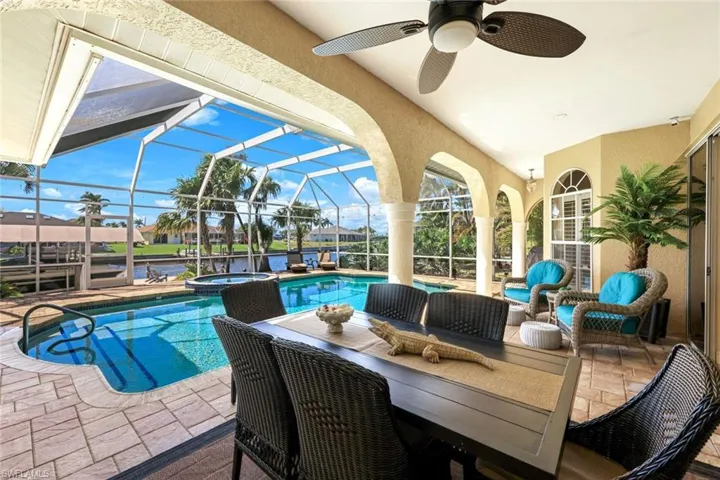 View of pool with a lanai, a patio, a pool with connected hot tub, and ceiling fan