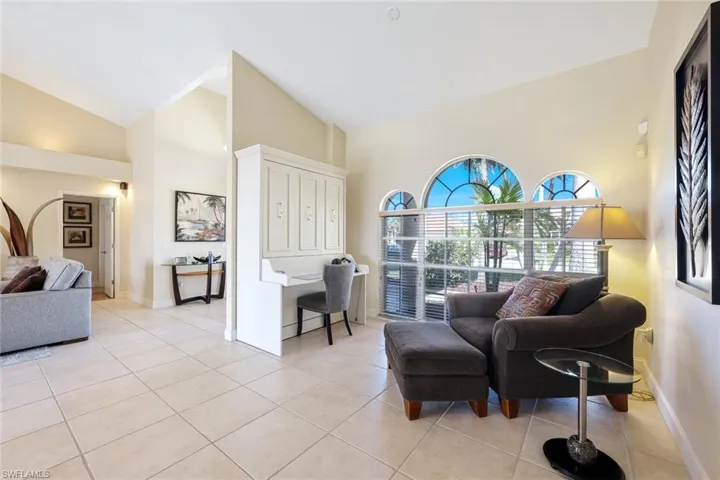 Living area featuring light tile patterned floors, baseboards, and high vaulted ceiling