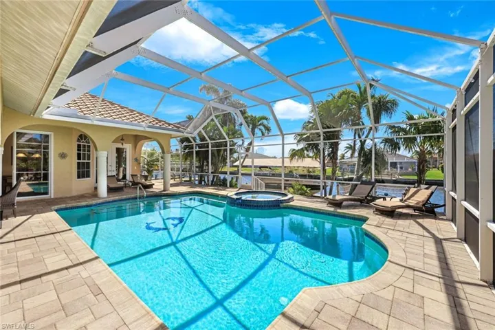 View of swimming pool featuring glass enclosure, a patio, and a pool with connected hot tub
