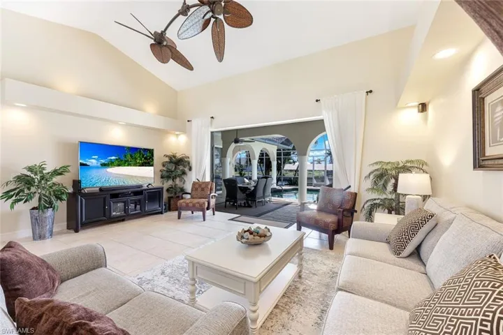 Living area featuring light tile patterned floors, high vaulted ceiling, and ceiling fan