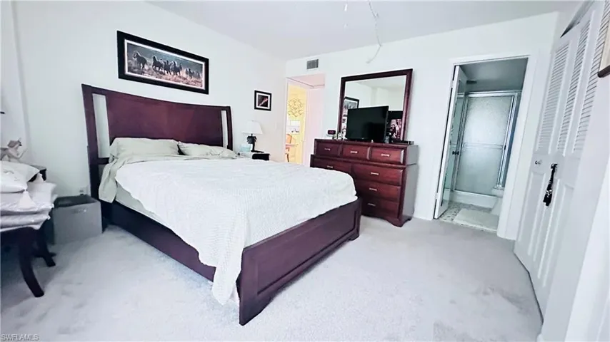 Bedroom with light colored carpet and ensuite bathroom