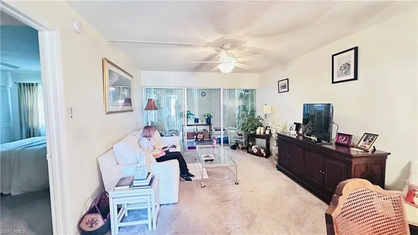Carpeted living room featuring a ceiling fan and a textured ceiling