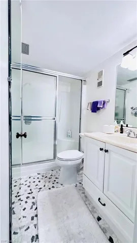 Full bathroom featuring an enclosed shower and vanity