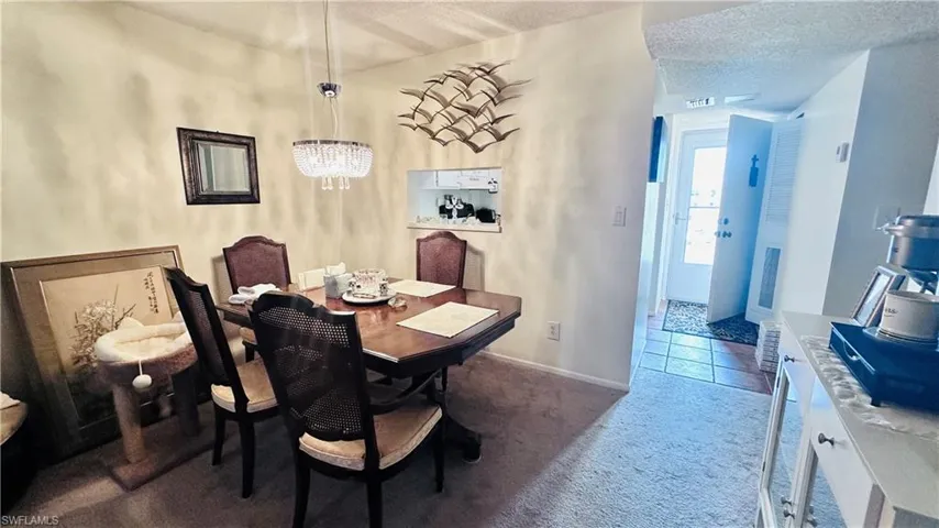 Carpeted dining area with a chandelier and baseboards