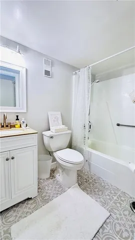 Full bath featuring vanity, shower / bathtub combination with curtain, and tile patterned flooring