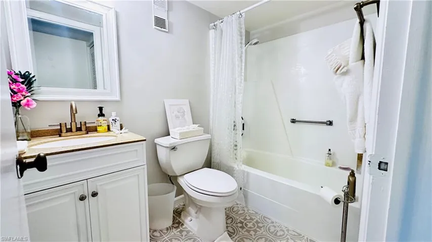 Bathroom featuring vanity, shower / bath combination with curtain, and tile patterned floors
