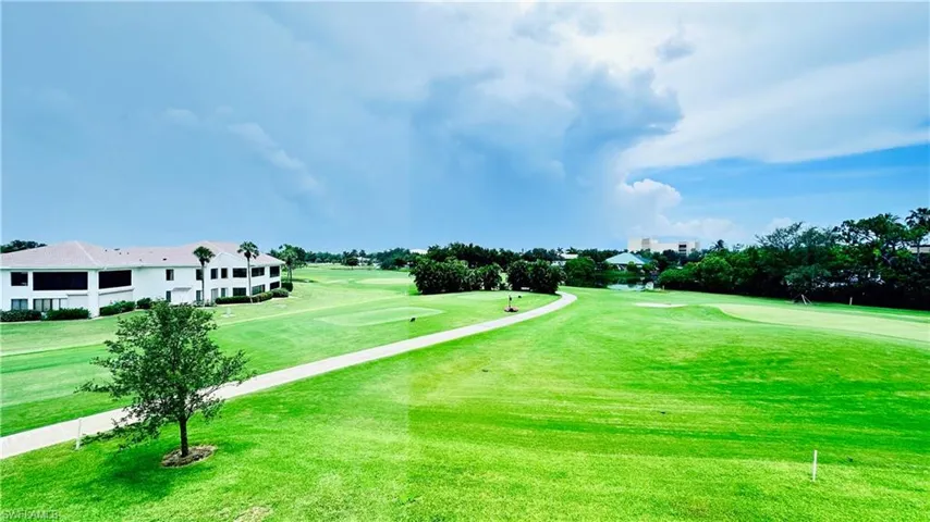 View of community featuring view of golf course, a lawn, and view of scattered trees