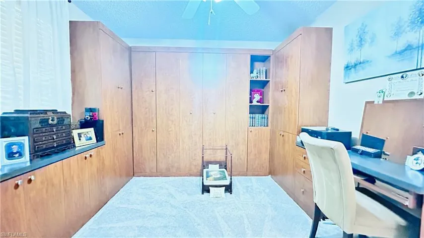Carpeted office space with a textured ceiling and a ceiling fan