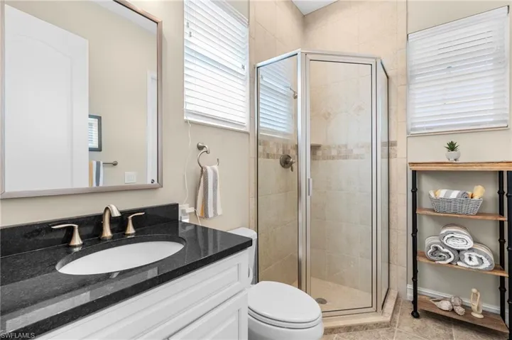 Bathroom featuring tile patterned flooring, vanity, toilet, and walk in shower