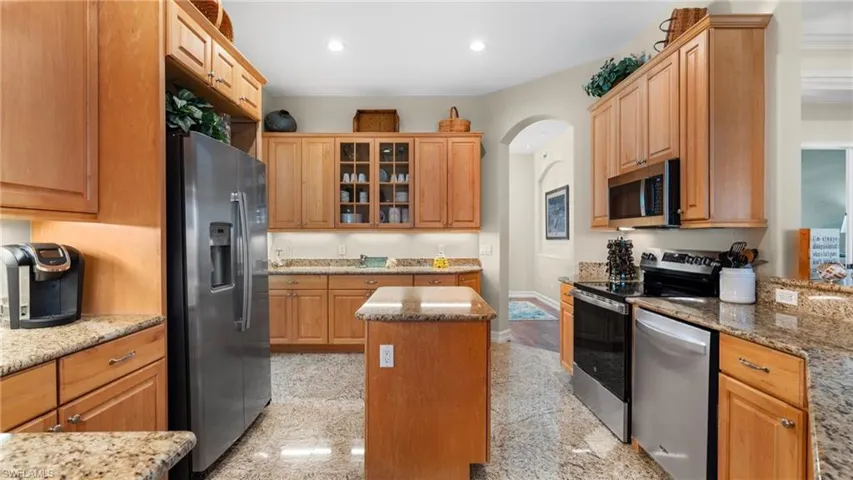 Kitchen featuring light stone counters, a kitchen island, and appliances with stainless steel finishes